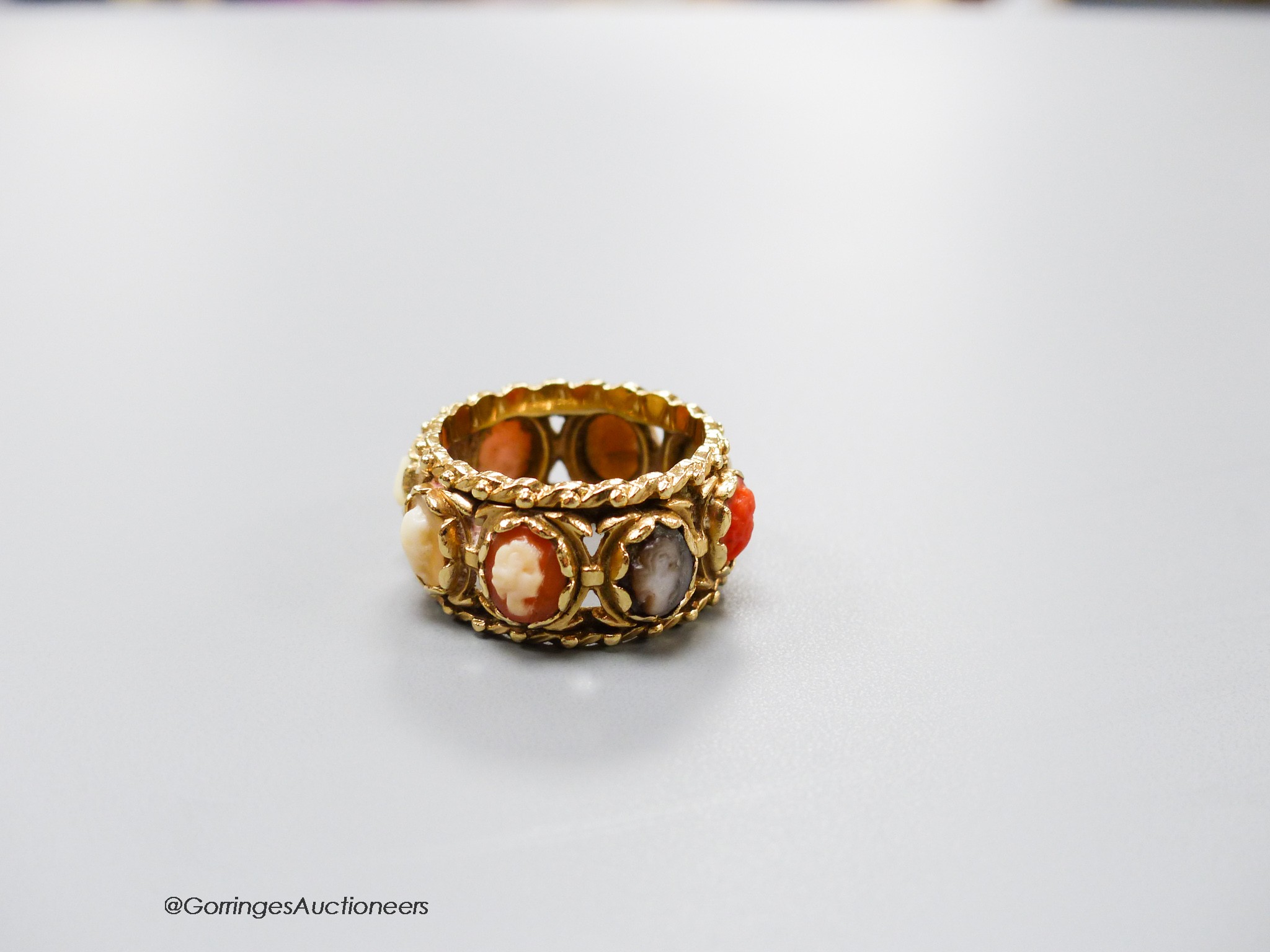 A 14kt yellow metal and multi cameo stone set eternity ring, including shell and coral, size P, gross weight 9.2 grams.